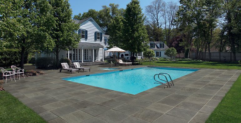 Kronos Pennsylvania collection color True Blue installed around a beautiful swimming pool outdoors.