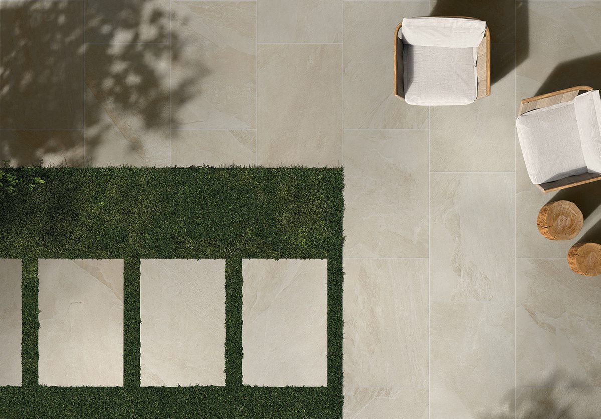 A patio is shown with 2cm pavers installed on concrete and loose laid in grass